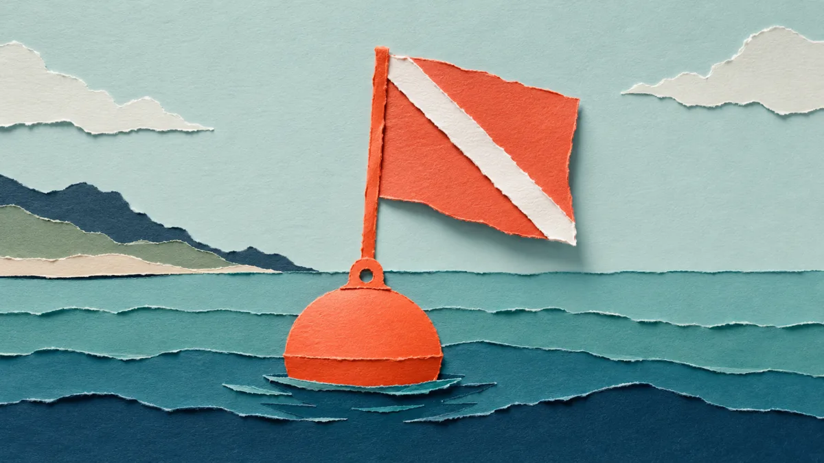 La boa con la bandiera rossa a striscia diagonale bianca ben visibile sulla superficie del mare